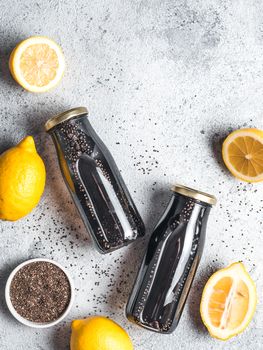 Detox activated charcoal black chia water or lemonade with lemon. Two bottle with black chia infused water. Detox drink idea and recipe. Vegan food and drink. Top view. Copy space for text. Vertical.