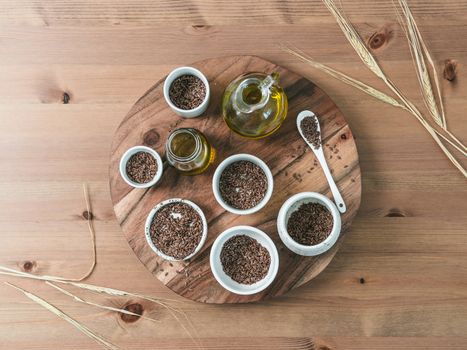 flax seeds and flaxseed oil on wooden table. Set of small bowls with organic flax seed or linen seed. Flax oil is rich in omega-3 fatty acid. Copy space. Top view or flat-lay.