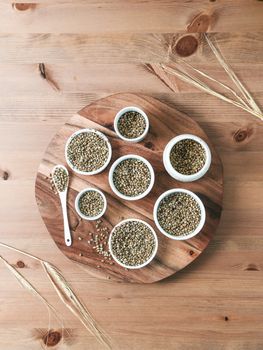 Hemp seeds in small white bowls and spoon on wooden table. Set of small bowls with raw organic unrefined hemp seed. Superfood and vegan concept. Top view or flat lay.Copy space for text