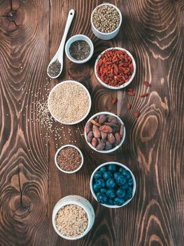 Various superfoods in small bowl on wooden table.Selection super food.Superfood as blueberry, chia, raw cocoa bean, goji, hemp seeds, quinoa, brown rice. Copy space.Top view or flat lay.Vertical