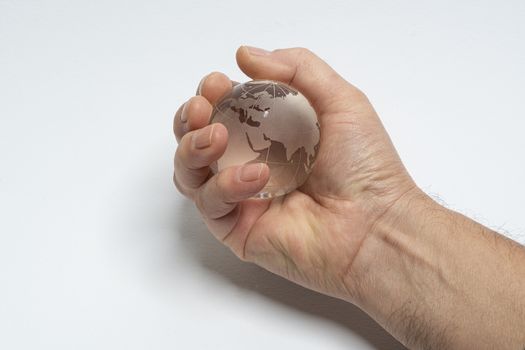 A male hand holds glass earth globe in the hand