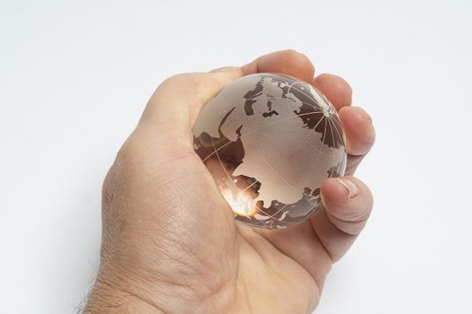 A male hand holds glass earth globe in the hand