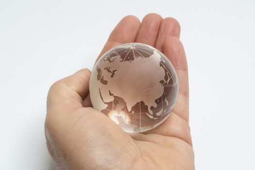 A male hand holds glass earth globe in the hand