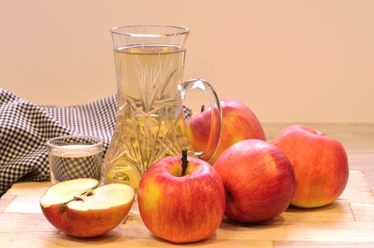 Apple cider vinegar in glass bottle and fresh apples on wooden background.