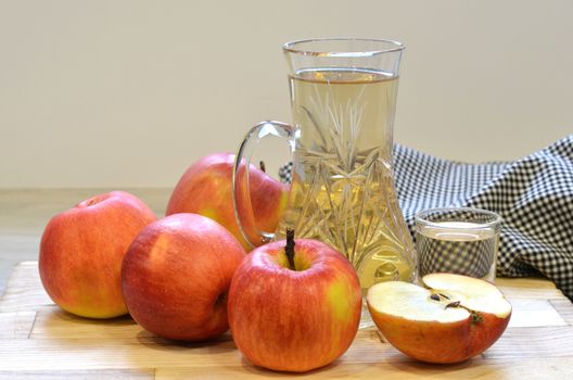 Apple cider vinegar in glass bottle and fresh apples on wooden background.