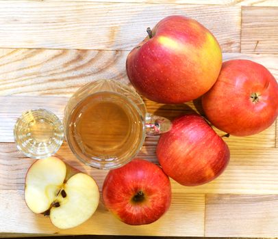 Apple cider vinegar in glass bottle and fresh apples on wooden background.