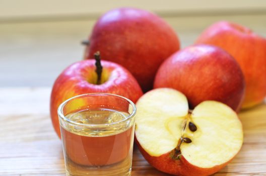 Apple cider vinegar in glass bottle and fresh apples on wooden background.