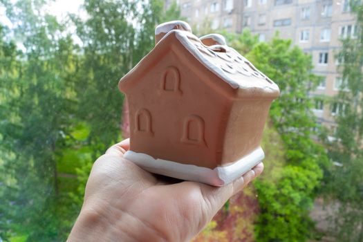 Toy brown house is in hand close-up. The concept of staying at home.