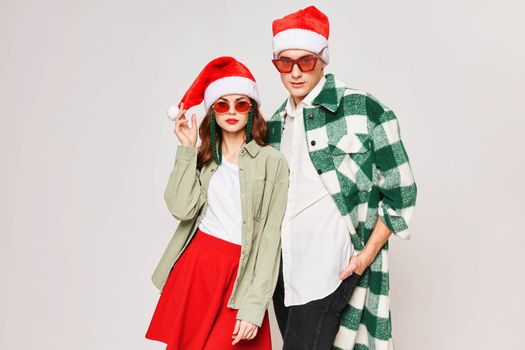 Young couple wearing sunglasses Santa hat Christmas winter holiday fashion. High quality photo