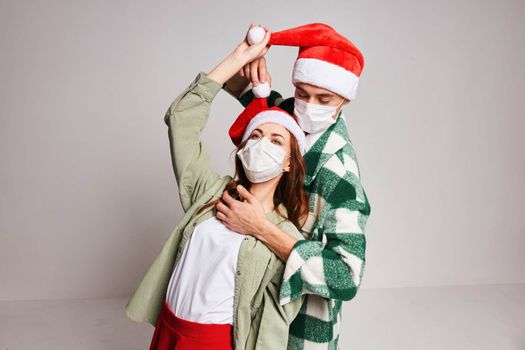 Man and woman embrace fun and holiday medical New Year masks. High quality photo