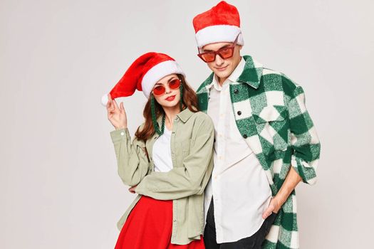 Man and woman in sunglasses Christmas hat hugs holiday Studio. High quality photo
