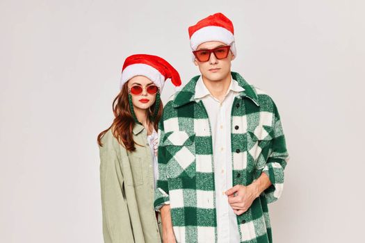 A man and a woman stand side by side in sunglasses Christmas holiday New Year hats friendship. High quality photo