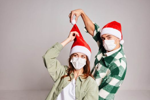 Family couple in medical masks on the face of Santa hat New Years winter hugs. High quality photo