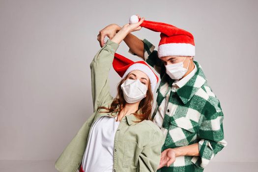 Man and woman having fun together in medical masks holiday Christmas gray background. High quality photo