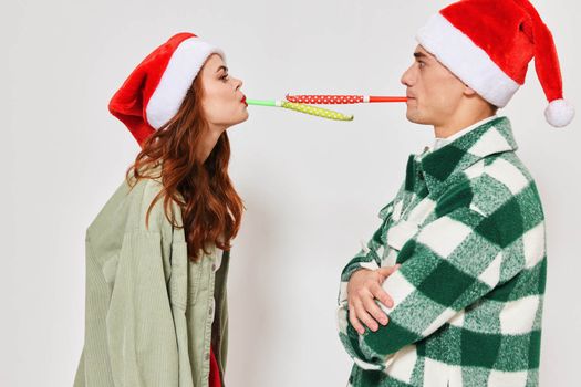 cute young couple in christmas hats multicolored pipes fun together holiday. High quality photo