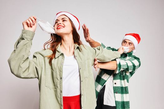 man and woman wearing christmas hats fun together holiday medical masks. High quality photo