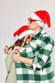 young couple wearing sunglasses christmas hats hugs care holiday. High quality photo