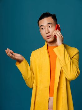 Asians guy in fashionable suit talking on the phone on a blue background. High quality photo