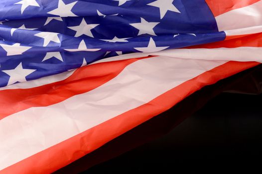 A closeup of an American flag over a black background with copyspace area for your text.