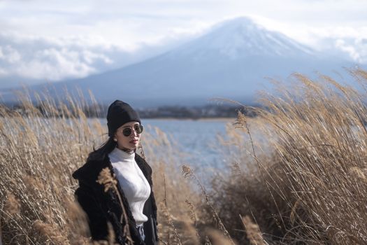 Beautiful smiling woman tourists are traveling and feel happy with Mt Fuji in the morning on the lake kawaguchiko, Japan