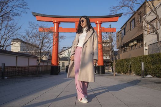 Young woman tourist travel Kyoto, Japan at Fushimi Inari Shrine main gate at sunrise