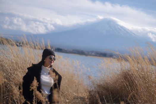 Beautiful smiling woman tourists are traveling and feel happy with Mt Fuji in the morning on the lake kawaguchiko, Japan