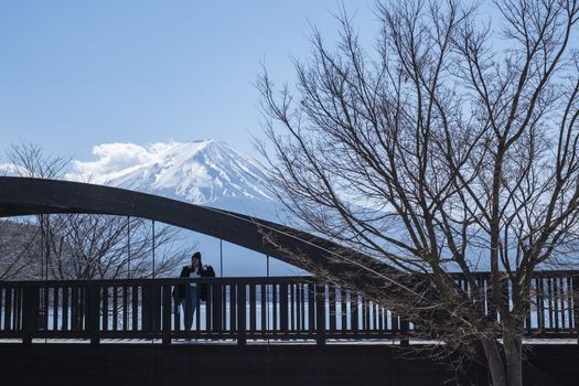 Beautiful smiling woman tourists are traveling and feel happy with Mt Fuji in the morning on the lake kawaguchiko, Japan