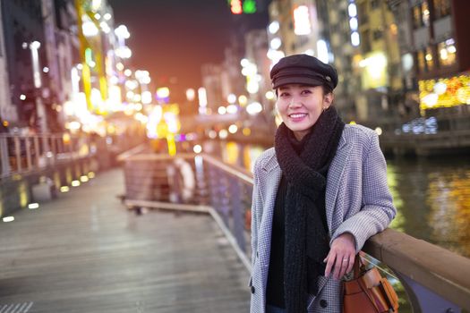 Beautiful smiling woman tourists traveling in walking at street shopping center Dotonbori in Osaka, Japan.
