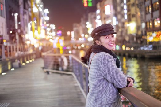 Beautiful smiling woman tourists traveling in walking at street shopping center Dotonbori in Osaka, Japan.