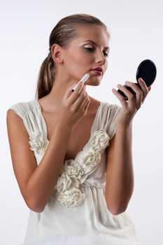 Young beautiful woman applying cosmetics onto her face