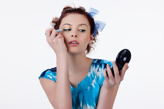 Young beautiful woman applying cosmetics onto her face