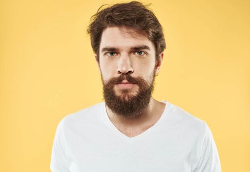 A man with a beard and mustache on a yellow background and a white T-shirt. High quality photo