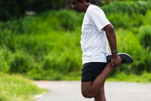 Close up Asian young athlete sport runner black man wear watch lift feet stretching legs and knee before running at the outdoor street health park, healthy exercise before workout concept