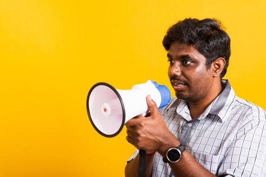 Asian happy portrait young black woman standing to make announcement message shouting screaming in megaphone, studio shot isolated on yellow background with copy space