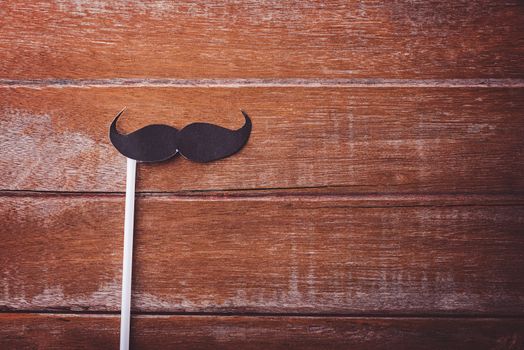 Black mustache paper on wooden background, Prostate cancer awareness month, Fathers day, minimal November moustache concept