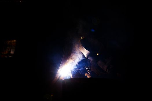 A welder is welding a metal pipe with electric welding.