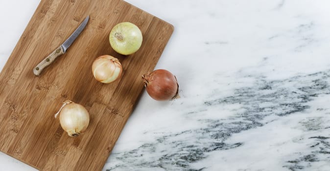 Fresh raw organic onions on marble stone with cutting board