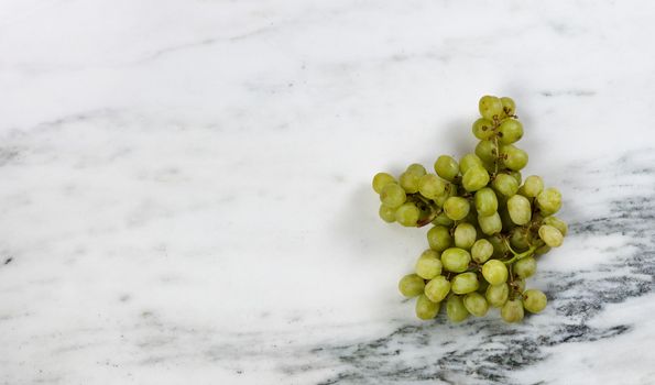 Fresh organic raw grapes on marble stone table in overhead view 