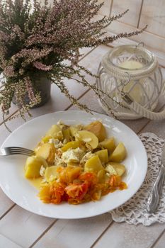 boiled potatoes with peper salad on the white plate, shabby wooden table