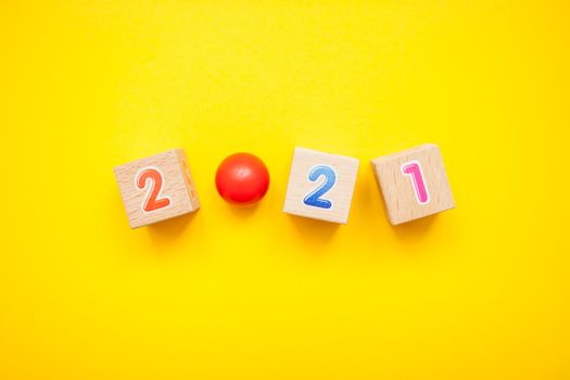 Numbers 2021 from children's cubes on a bright yellow background. New Year Christmas