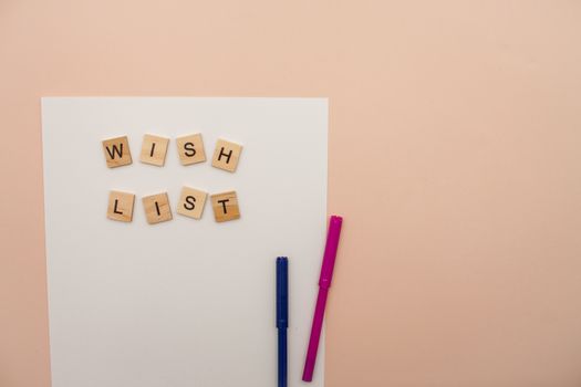 Inscription from wooden blocks wish list on a white blank sheet of paper. New Year's wish list. Letter to Santa Claus