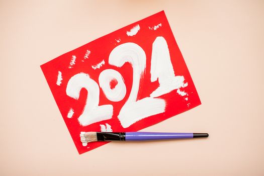 The numbers 2021 are written in white paint on a red sheet of paper. New Year. Christmas