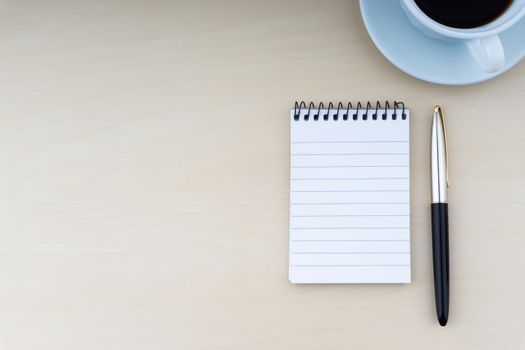 Fountain pen, notepad and cup of coffee on wooden background. Business and copy space concept.
