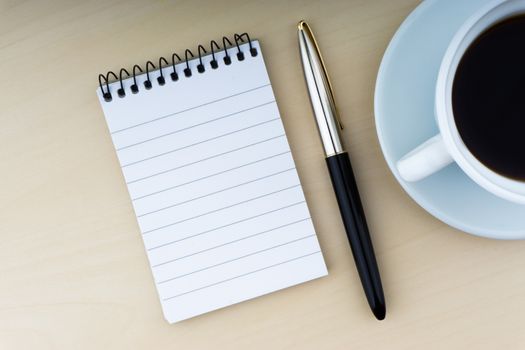 Fountain pen, notepad and cup of coffee on wooden background. Business and copy space concept.

