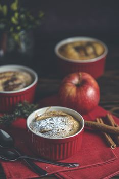 Three apple pies in ceramic baking molds with red napkin ramekin on dark wooden table. Close up, shallow depth of the field.