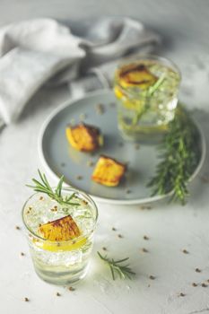 Two glasses of Charred Lemon, Rosemary and Coriander Gin and Tonic is a flavors are perfectly balanced refreshing cocktail. on light background, close up. Summer drinks and alcoholic cocktails