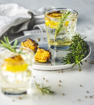 Two glasses of Charred Lemon, Rosemary and Coriander Gin and Tonic is a flavors are perfectly balanced refreshing cocktail. on light background, close up. Summer drinks and alcoholic cocktails