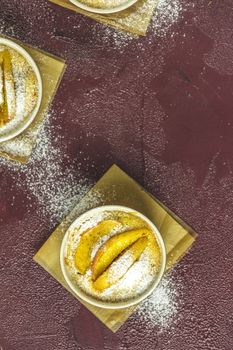 Three apple pies in ceramic baking molds with napkin ramekin on dark red concrete table. Top view, flat lay.