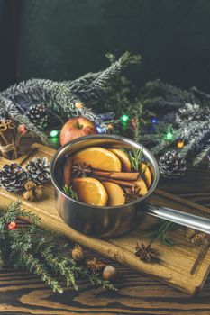 Christmas mulled red wine with the addition of spices and citrus fruits in a small metal pan on a rustic wooden table, top view. Pot of mulled wine, traditional christmas drink.