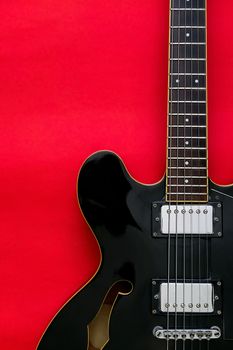 Detail of Electric Guitar on a red background.